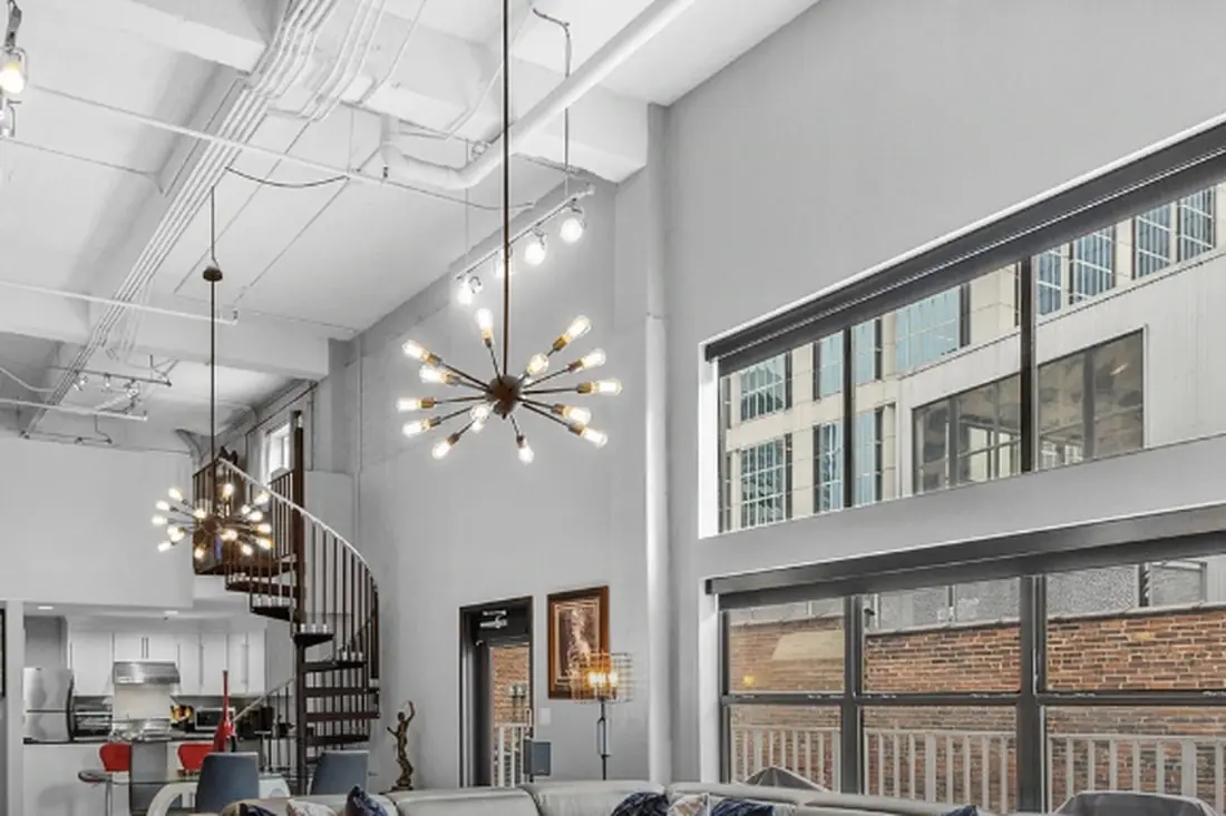 Two-storey loft living room with exposed ductwork and tall windows
