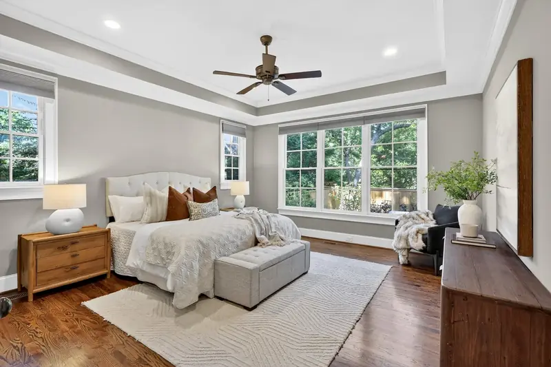 Primary bedroom with tray ceiling and hardwood floors