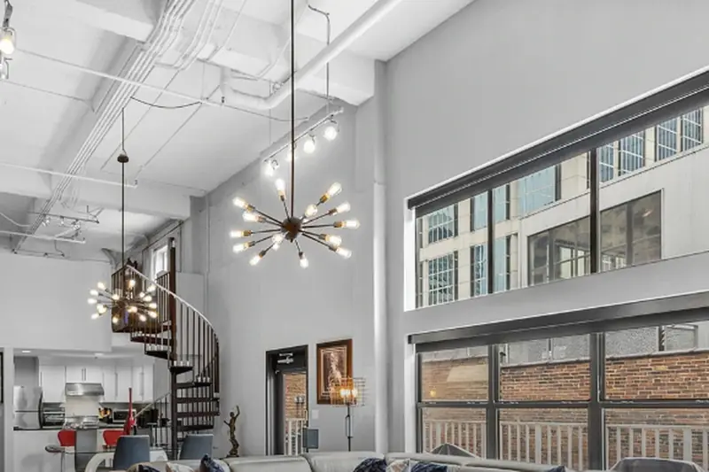 Two-storey loft living room with exposed ductwork and tall windows